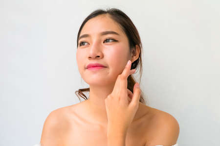 Beautiful young woman with healthy clean skin presenting something on her hand. Isolated on white. asian beautyの写真素材
