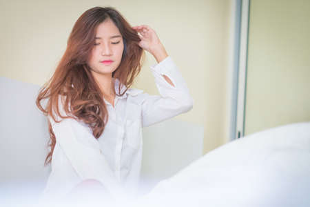 Elegant beautiful woman wearing white shirt posing in bedroom,の写真素材