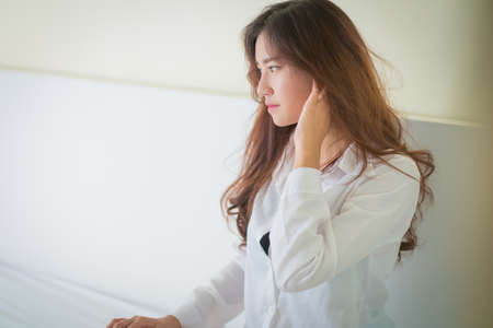 Elegant beautiful woman wearing white shirt posing in bedroom,の写真素材