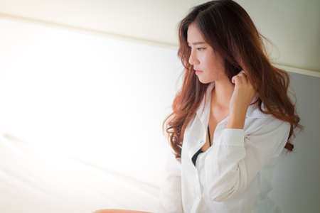 Elegant beautiful woman wearing white shirt posing in bedroom,の写真素材