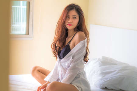Sexy portrait in vintage style. Beautiful woman in white bathrobe in bedroom , Lighting with sun flareの写真素材