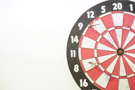 Two old darts on an old dart board with many holes. Concept of competition; failed attempt (missed target); no skill; or no improvement. White background and copy space on the left.の写真素材