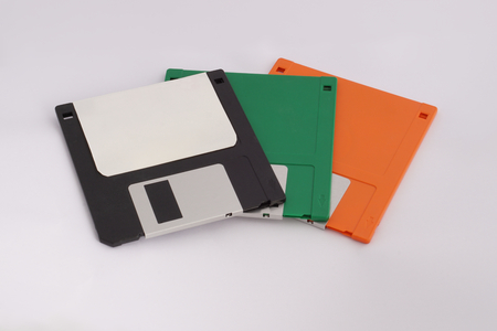 Three floppy disks (black, green, and orange) on white background.