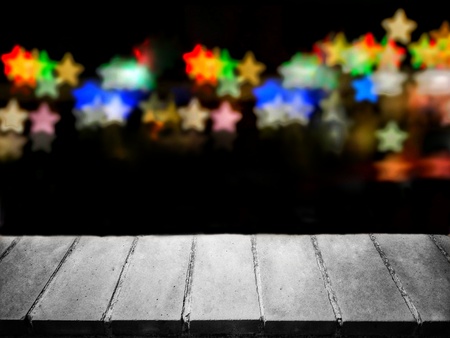 Concrete surface in front of colorful stars bokeh in dark background. Use for mock-up template, image montage, backdrop in concepts of romantic, Christmas, new year.の写真素材