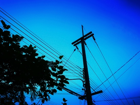 Silhouette of power lines, telephone transmission wires installed on the same poleの写真素材