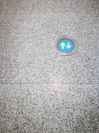 Green arrows sign on granite floor in public transport station or airport passenger terminal. There are copy-space on the left and below of image.の写真素材
