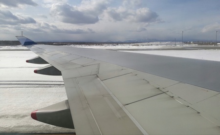 Airplane wing taken from plane window, moving on ground at an airport, mountain background, blue sky and snow covering in whole area. Useful as visual content for technology, education, tourism, etc.の写真素材