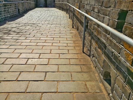 Close up of ancient stone trail on the Great Wall of China - slope pathway with installed handrail...