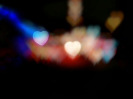 Abstract blur light of two hearts among colorful heart bokeh on black background; taken from colorful flashlights decorated on trees at night - Bottom copy space. Concepts of love and valentine.の写真素材