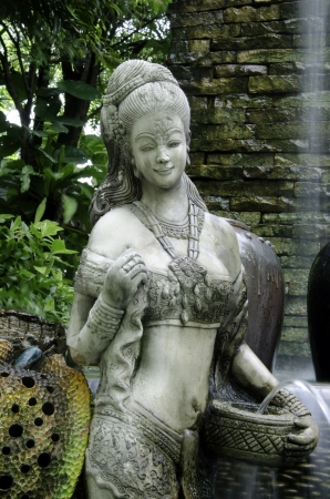 Statue of a young woman with a water fall backdrop.の写真素材
