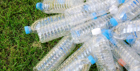 Pile from plastic bottles with a lawn in the background.の写真素材