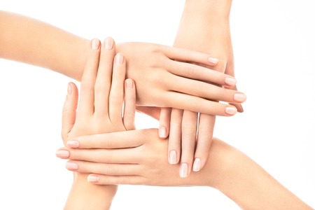 Four female hands placed one over another with french nail design on white background