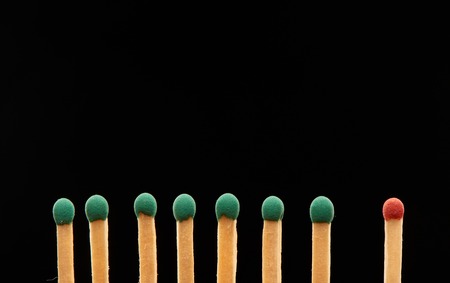 Set of seven green and one red wooden matches isolated on black background