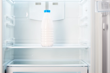 Bottle of yoghurt on shelf of open empty refrigerator. Weight loss diet concept.の写真素材