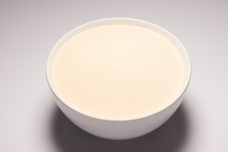 Semolina croup in white ceramic bowl on white backgroundの写真素材