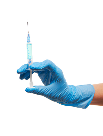 Close up of female doctor's hand in blue sterilized surgical glove with plastic medical syringe filled with blue drug against white backgroundの写真素材