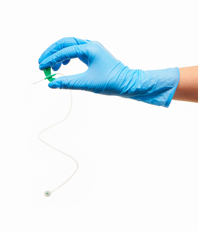 Close up of female doctor's hand in blue sterilized surgical glove with green plastic catheter against white backgroundの写真素材