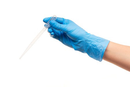 Close up of female doctor's hand in blue sterilized surgical glove with white plastic medical dropper against white backgroundの写真素材