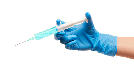 Close up of female doctor's hand in blue sterilized surgical glove with plastic medical syringe filled with blue drug against white backgroundの写真素材