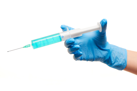 Close up of female doctor's hand in blue sterilized surgical glove with plastic medical syringe filled with blue drug against white backgroundの写真素材