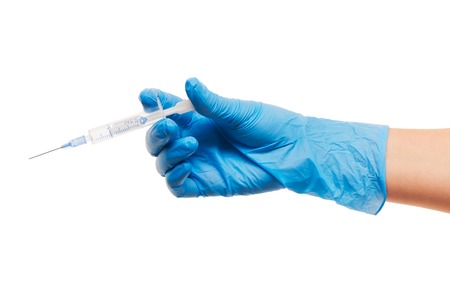 Close up of female doctor's hand in blue sterilized surgical glove with plastic medical syringe against white backgroundの写真素材