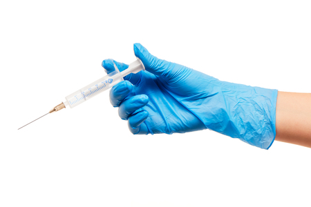 Close up of female doctor's hand in blue sterilized surgical glove with plastic medical syringe against white backgroundの写真素材