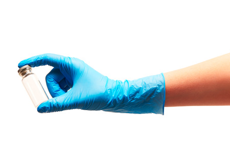 Close up of female doctor's hand in blue sterilized surgical glove holding empty transparent white glass ampoule against white backgroundの写真素材