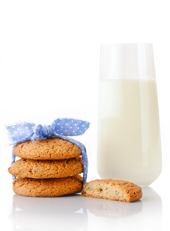 Stack of three homemade oatmeal cookies tied with blue ribbon in small white polka dots, half of cookie and glass of milk, isolated on white backgroundの写真素材