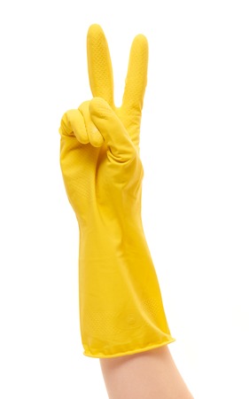 Close up of female hand in yellow protective rubber glove showing victory sign against white backgroundの写真素材