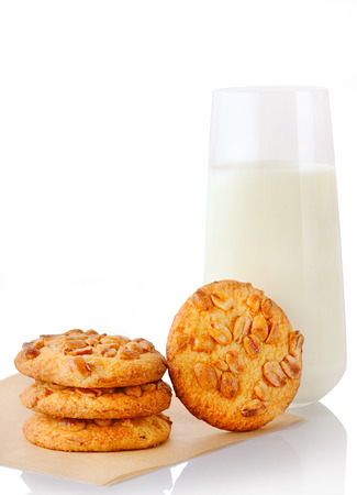 Stack of three homemade peanut butter cookies on baking paper, single cookie and glass of milk, isolated on white backgroundの写真素材