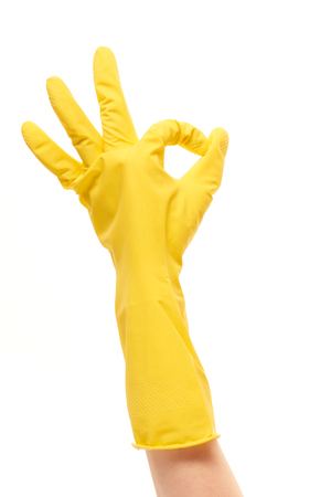 Close up of female hand in yellow protective rubber glove showing OK sign against white backgroundの写真素材