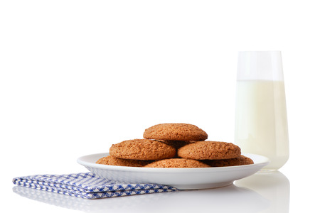Pile of homemade oatmeal cookies on white ceramic plate on blue napkin and glass of milk, isolated on white backgroundの写真素材