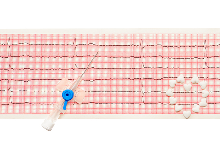 Heart made of white heart shape tablets and blue plastic catheter with open needle on paper ECG results isolated on white background. Clipping path included.の写真素材