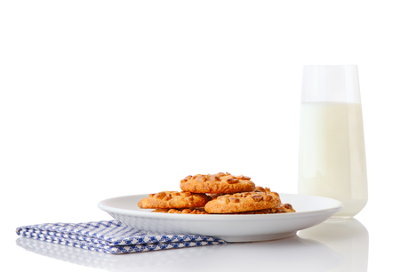 Pile of homemade peanut butter cookies on white ceramic plate on blue napkin and glass of milk, isolated on white backgroundの写真素材