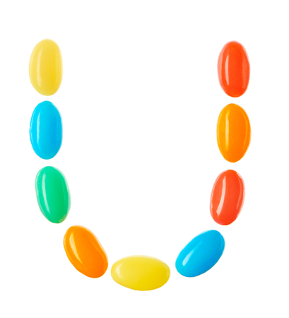 U letter made of multicolored candies isolated on white backgroundの写真素材