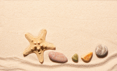 Starfish and sea stones on sand. Summer beach background. View from aboveの写真素材