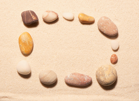 Rectangular frame of sea stones on sand. Summer beach background. View from aboveの写真素材