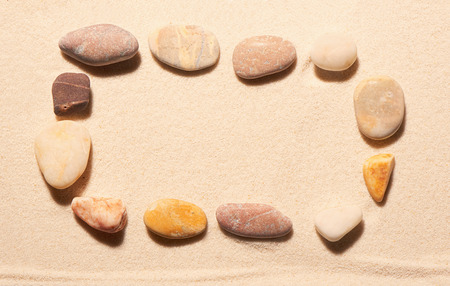 Rectangular frame of sea stones on sand. Summer beach background. View from aboveの写真素材