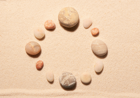 Round frame of sea stones on sand. Summer beach background. View from aboveの写真素材