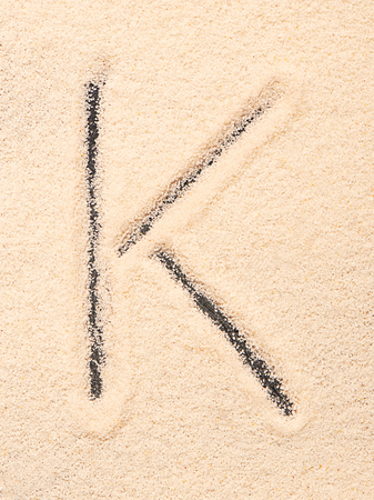 K letter written on sandの写真素材