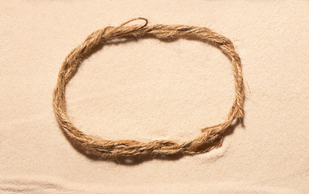 Oval frame of rope on sand. Summer beach background. View from aboveの写真素材