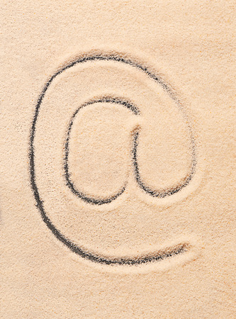 AT symbol, email address icon drawn on sand. Summer beach backgroundの写真素材