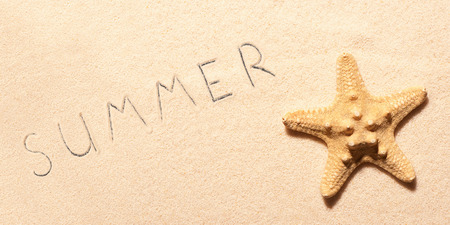Starfish on sand and summer lettering drawn on sand. Summer beach background. View from aboveの写真素材