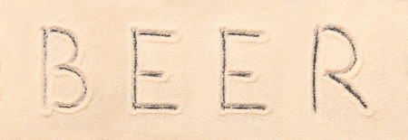 Beer lettering drawn on sand. Summer beach backgroundの写真素材