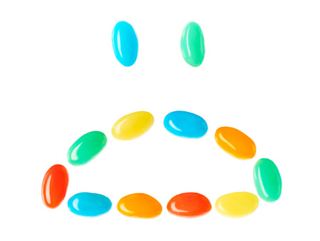 Upset sad smiley made of multicolored candies isolated on white backgroundの写真素材