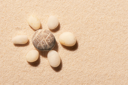 Flower made of sea stones on sand. Summer beach background. View from aboveの写真素材