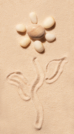 Flower made of sea stones with stem and leaves drawn on sand. Summer beach background. View from aboveの写真素材