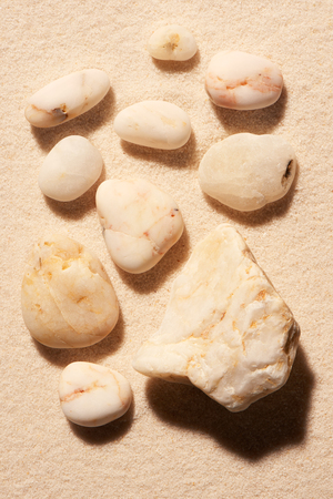 Collection of ten white toned sea stones on sand. Summer beach background. View from aboveの写真素材