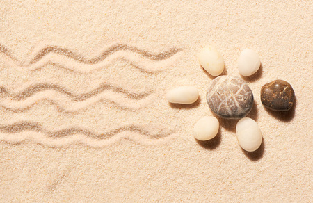 Turtle made of sea stones with marks of tail and legs on sand. Summer beach background. View from aboveの写真素材