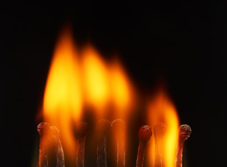 Set of eight burning wooden matches, isolated on black backgroundの写真素材